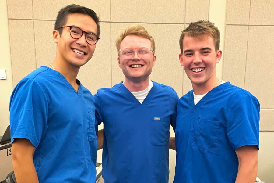 Three men in medical scrubs pose for a group photo